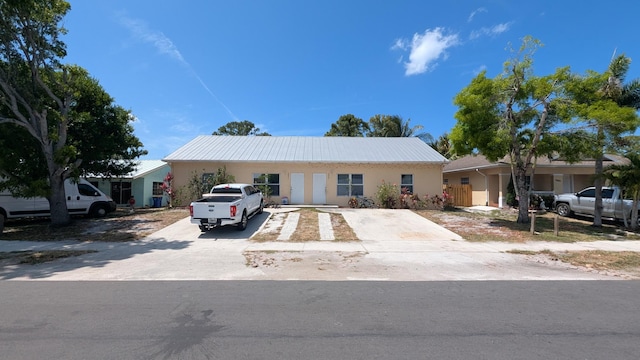 ranch-style home with stucco siding and metal roof