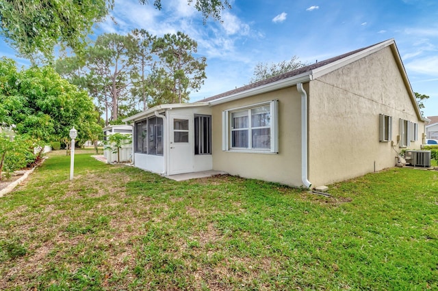 3516 Westminster Dr, Greenacres, FL 33463 - back of property featuring a sunroom, central AC unit, stucco siding, and a lawn