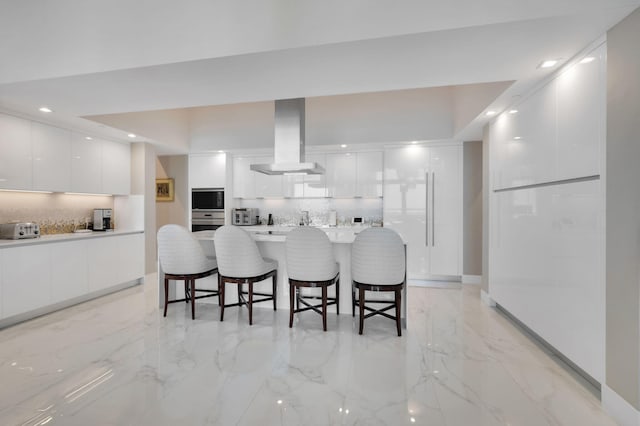 20155 Boca W Dr Unit Phc902, Boca Raton, FL 33434 - kitchen with modern cabinets, ventilation hood, a kitchen bar, backsplash, and white cabinets