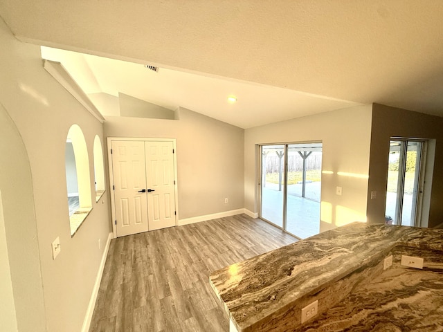 673 SW Granadeer St, Port Saint Lucie, FL 34983 - unfurnished bedroom with lofted ceiling, baseboards, wood finished floors, arched walkways, and access to exterior