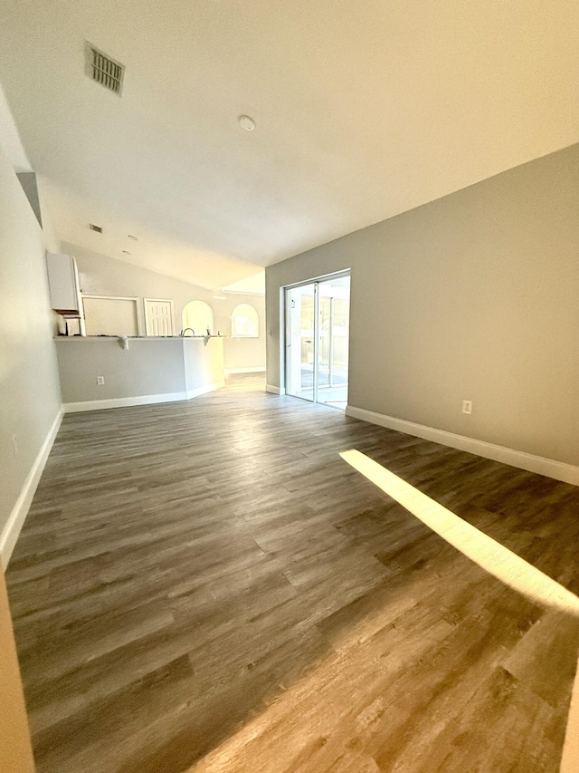 673 SW Granadeer St, Port Saint Lucie, FL 34983 - unfurnished living room featuring dark wood-style flooring, vaulted ceiling, baseboards, and visible vents