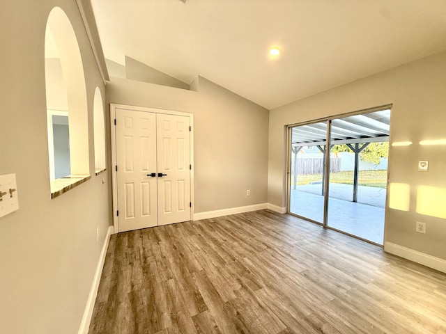 673 SW Granadeer St, Port Saint Lucie, FL 34983 - empty room with lofted ceiling, arched walkways, baseboards, and wood finished floors