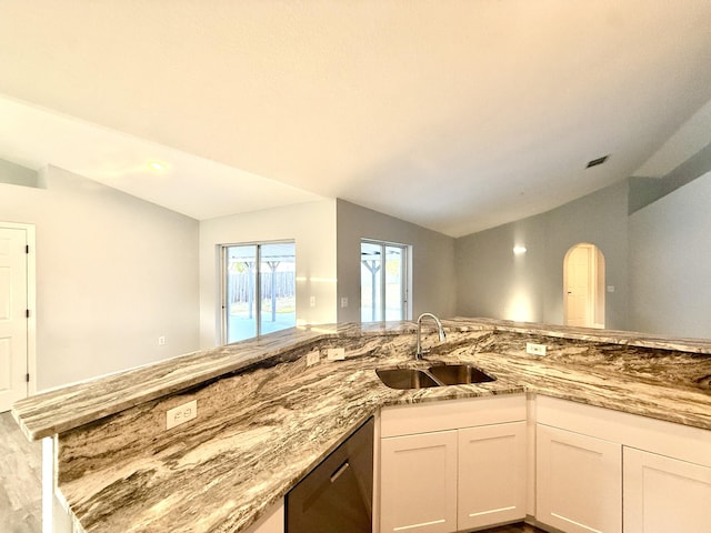 673 SW Granadeer St, Port Saint Lucie, FL 34983 - kitchen with lofted ceiling, stainless steel dishwasher, light stone counters, a sink, and white cabinets