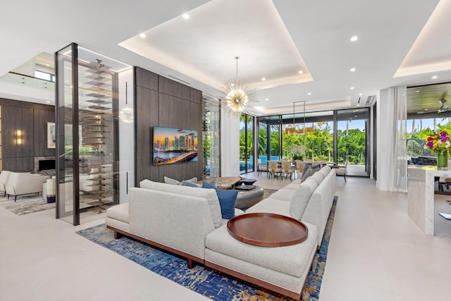 living room with a raised ceiling, recessed lighting, expansive windows, and a chandelier