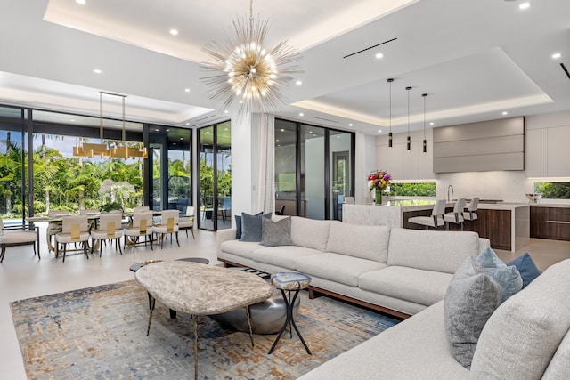 living room featuring a raised ceiling, a wall of windows, healthy amount of natural light, recessed lighting, and a chandelier