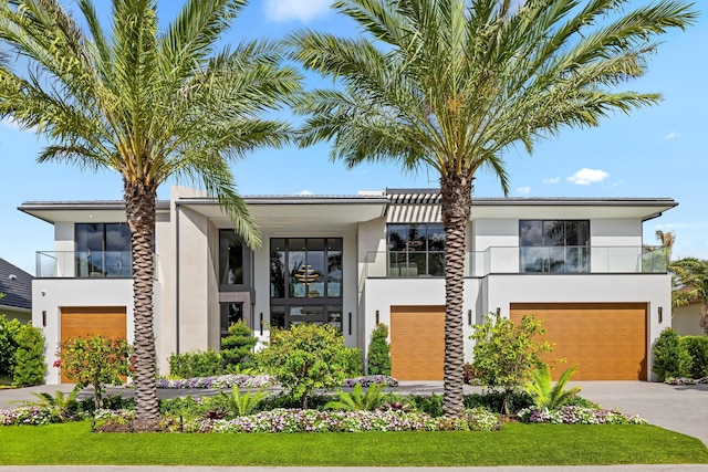 modern home with stucco siding, an attached garage, a balcony, and concrete driveway