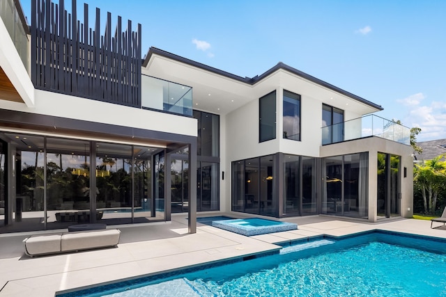 back of house with a balcony, a patio area, an outdoor pool, and stucco siding