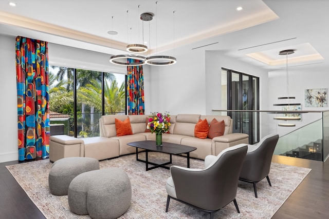 living area with a raised ceiling, wood finished floors, and recessed lighting