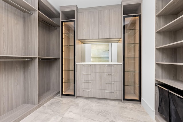 walk in closet featuring light marble finish floors