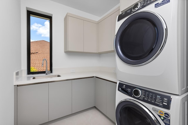 clothes washing area with stacked washer / drying machine and cabinet space