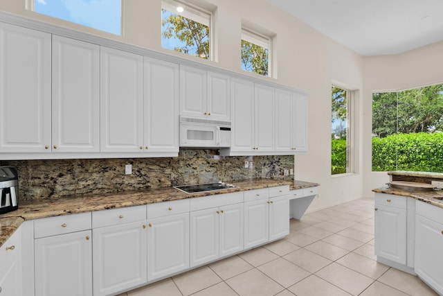 kitchen with black electric cooktop, decorative backsplash, light tile patterned floors, and white microwave
