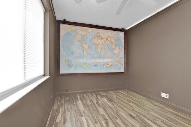 empty room featuring baseboards, light wood finished floors, and ceiling fan