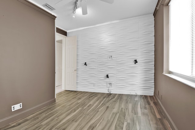 spare room featuring visible vents, baseboards, ceiling fan, and wood finished floors