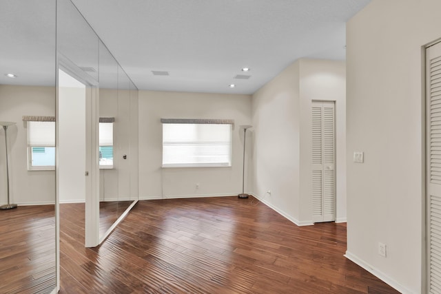 interior space with baseboards, recessed lighting, wood finished floors, and visible vents