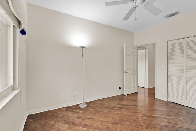 unfurnished bedroom featuring ceiling fan, baseboards, wood finished floors, visible vents, and a closet