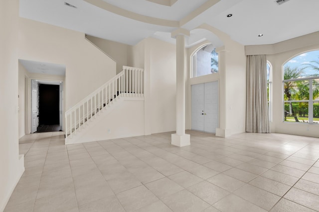 unfurnished living room with stairs, visible vents, a healthy amount of sunlight, and light tile patterned floors