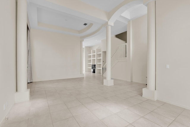 spare room with visible vents, arched walkways, a tray ceiling, stairs, and light tile patterned flooring