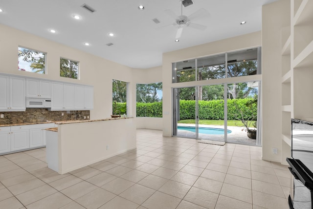 kitchen featuring visible vents, a healthy amount of sunlight, white microwave, tasteful backsplash, and a ceiling fan
