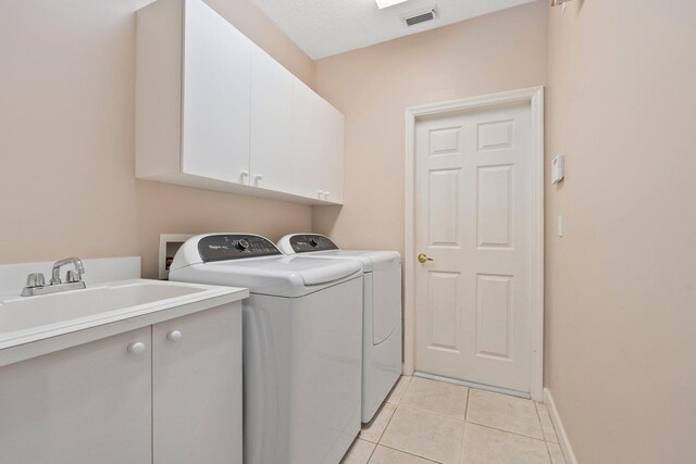 laundry area featuring visible vents, cabinet space, light tile patterned floors, a sink, and separate washer and dryer