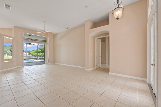 empty room featuring visible vents, baseboards, ceiling fan, arched walkways, and light tile patterned floors