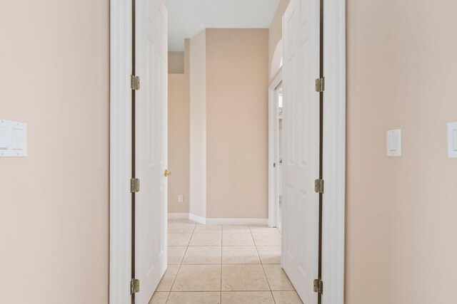 hallway featuring baseboards and light tile patterned floors