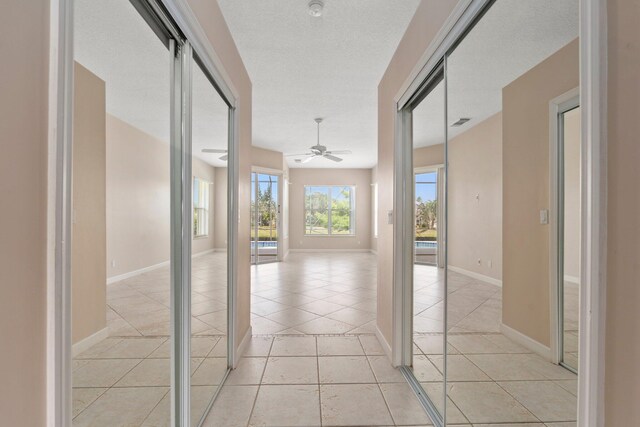 corridor featuring light tile patterned flooring, baseboards, and visible vents