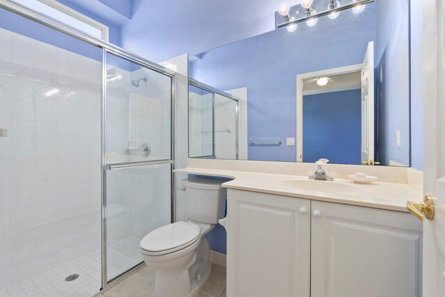 full bathroom featuring vanity, tile patterned floors, a stall shower, and toilet