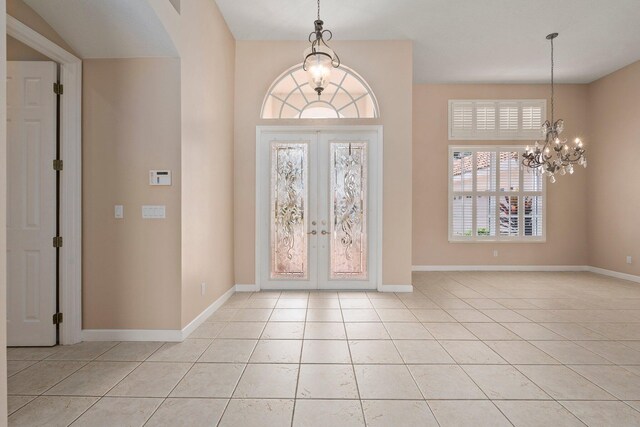 entryway with arched walkways, a chandelier, french doors, baseboards, and light tile patterned floors