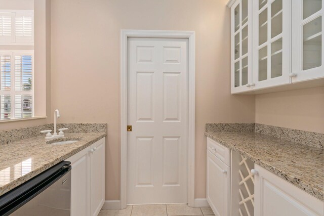 interior space featuring indoor wet bar, light tile patterned floors, baseboards, and a sink