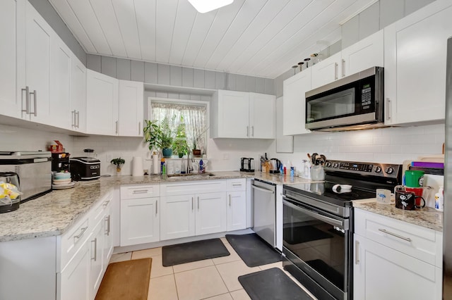 431 Virginia Dr, Lake Worth Beach, FL 33461 - kitchen with stainless steel appliances, light tile patterned floors, white cabinetry, tasteful backsplash, and a sink