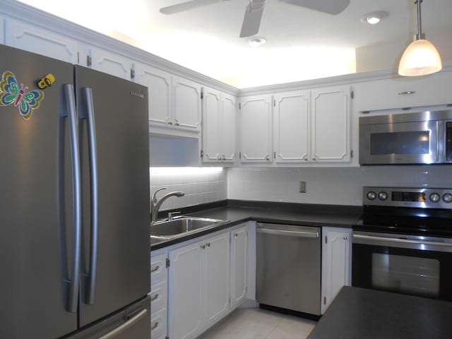 kitchen featuring decorative backsplash, dark countertops, appliances with stainless steel finishes, a sink, and white cabinets
