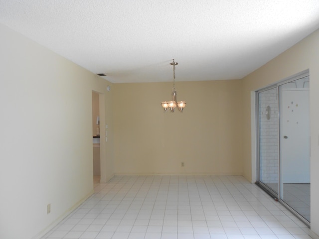 unfurnished room with a textured ceiling, a chandelier, and baseboards