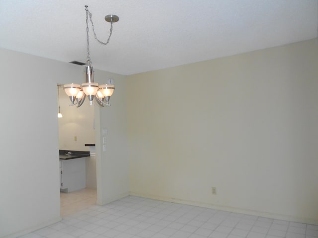 unfurnished room with an inviting chandelier and baseboards