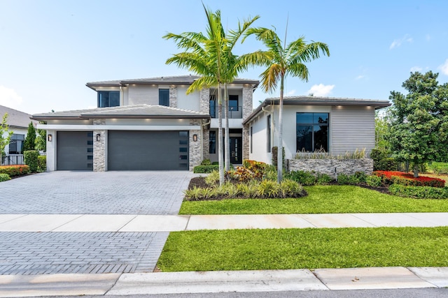 10715 Estuary Dr, Parkland, FL 33076 - prairie-style home featuring a balcony, stone siding, a front yard, decorative driveway, and an attached garage
