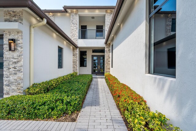 10715 Estuary Dr, Parkland, FL 33076 - view of exterior entry featuring a balcony, stucco siding, french doors, and stone siding
