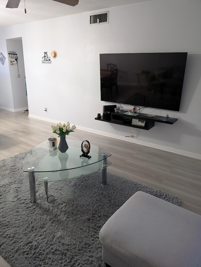 living area with visible vents, baseboards, ceiling fan, and wood finished floors