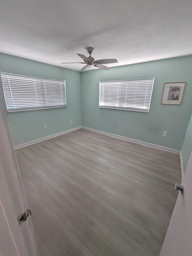 spare room featuring baseboards, ceiling fan, and wood finished floors