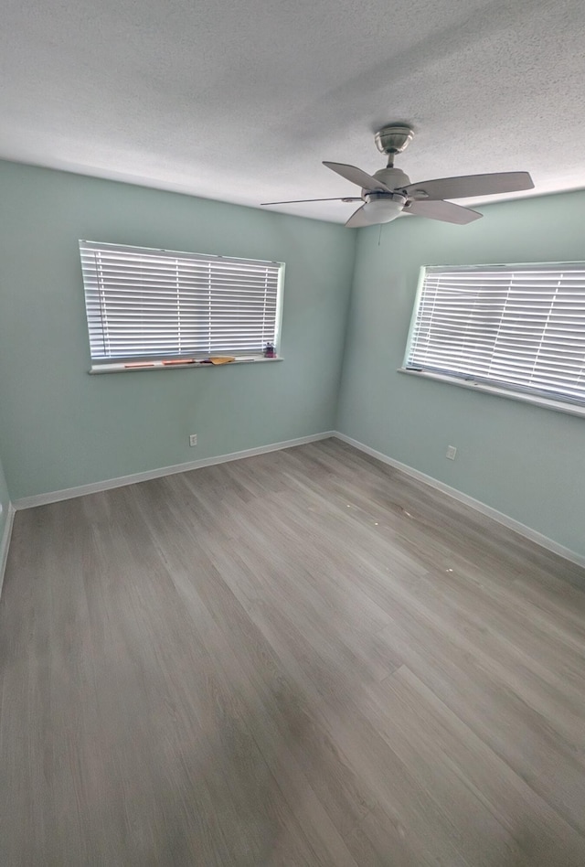 empty room featuring baseboards, ceiling fan, and wood finished floors