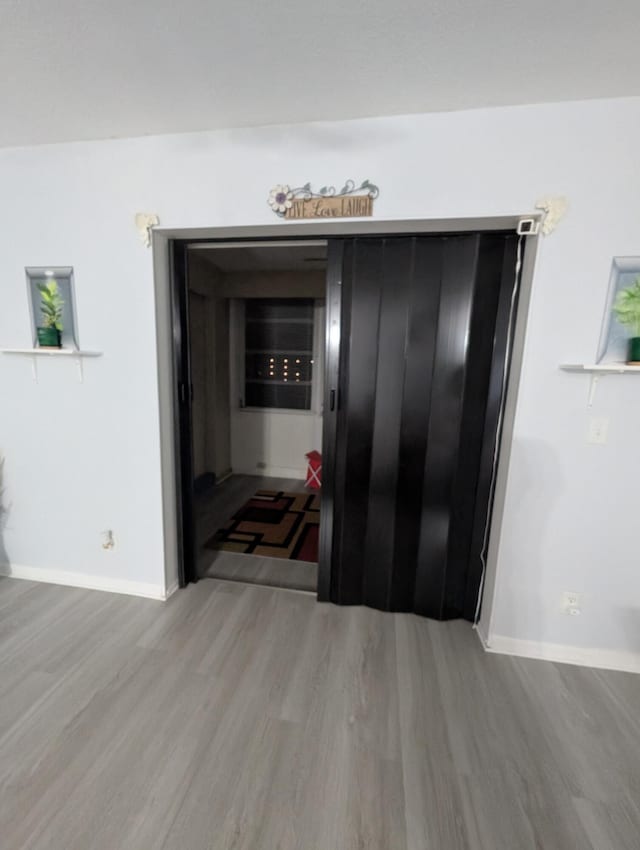 corridor featuring baseboards and wood finished floors