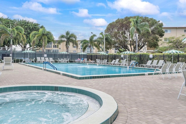 pool featuring a hot tub, a patio area, and fence