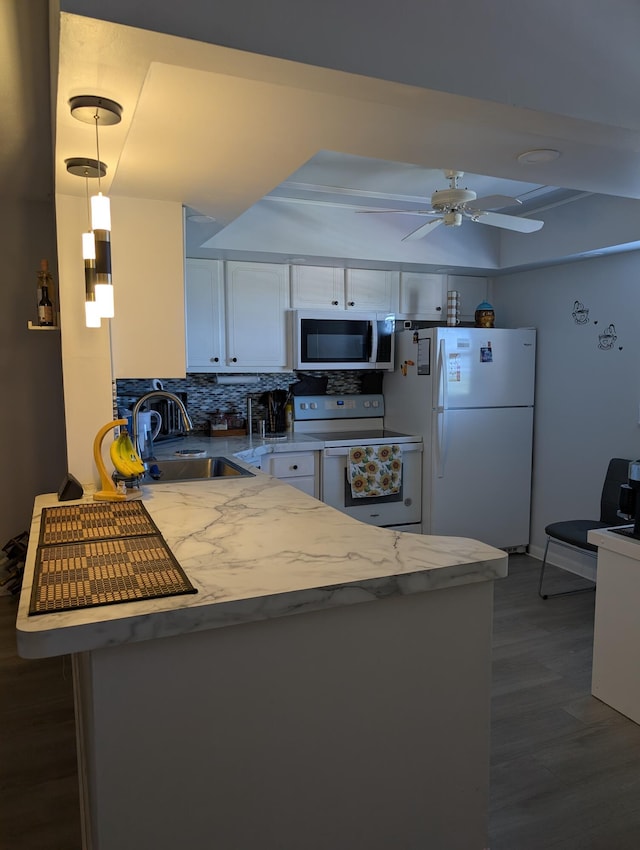 kitchen with white cabinets, a sink, white appliances, wood finished floors, and backsplash