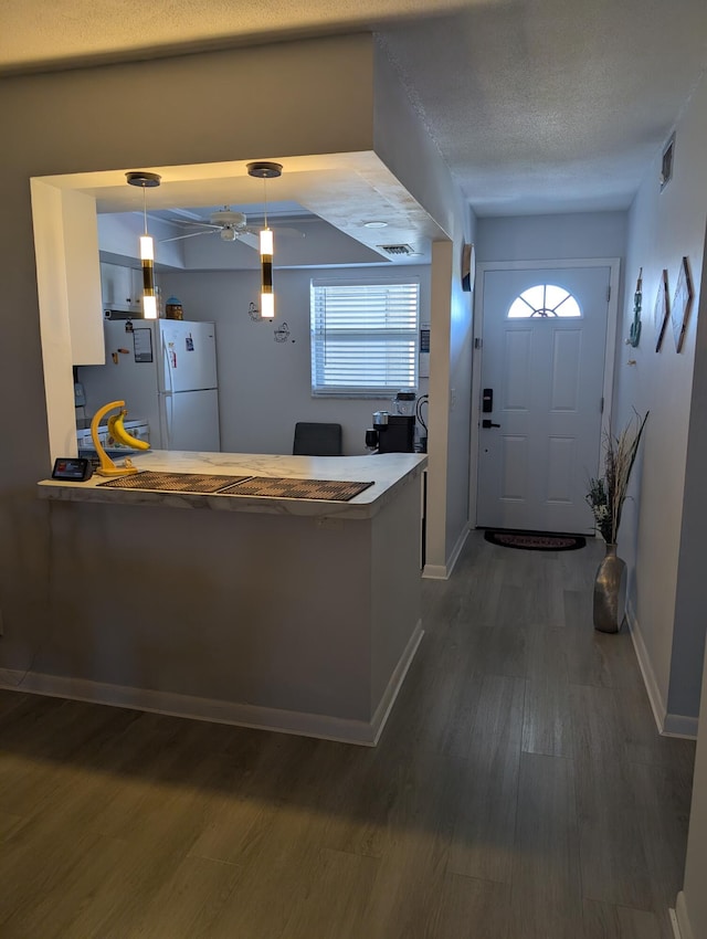 interior space with visible vents, a ceiling fan, dark wood-style flooring, and baseboards
