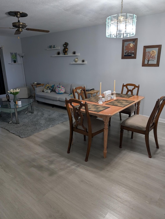dining space featuring ceiling fan with notable chandelier and light wood-style flooring