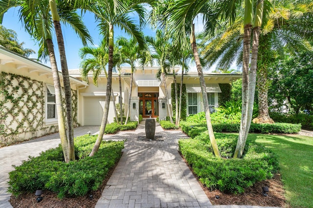 view of front facade featuring stucco siding, decorative driveway, and a garage