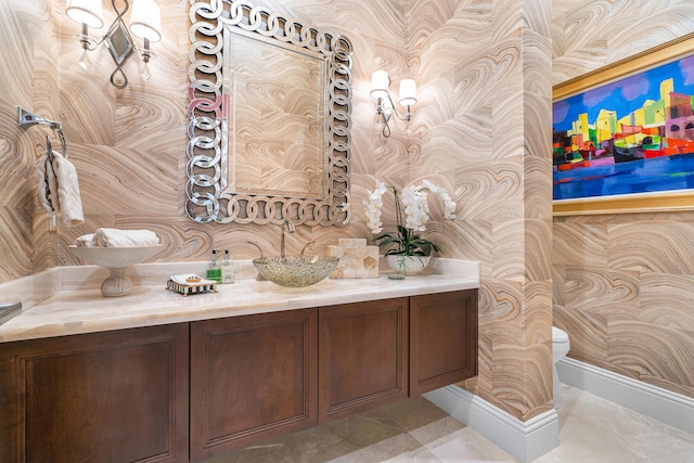 bathroom with vanity, baseboards, toilet, and wallpapered walls