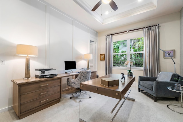 carpeted office space with crown molding, a ceiling fan, baseboards, and a tray ceiling