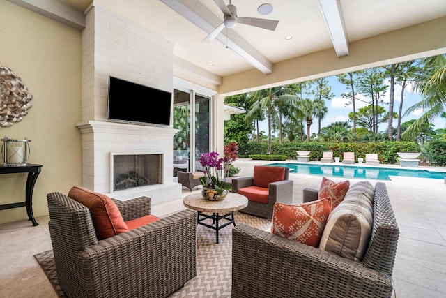 living room with beamed ceiling, exterior fireplace, and ceiling fan