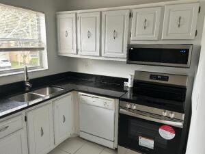 kitchen with a sink, light tile patterned floors, white cabinets, and stainless steel appliances
