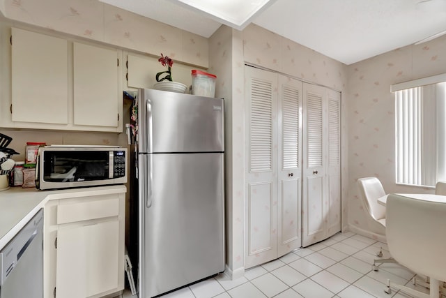 6585 Kensington Ln Unit 307, Delray Beach, FL 33446 - kitchen featuring appliances with stainless steel finishes, light countertops, light tile patterned flooring, wallpapered walls, and cream cabinetry