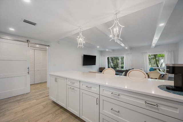 13334 Polo Club Rd Unit 234/235, Wellington, FL 33414 - kitchen featuring pendant lighting, light wood-style floors, a barn door, light countertops, and a notable chandelier